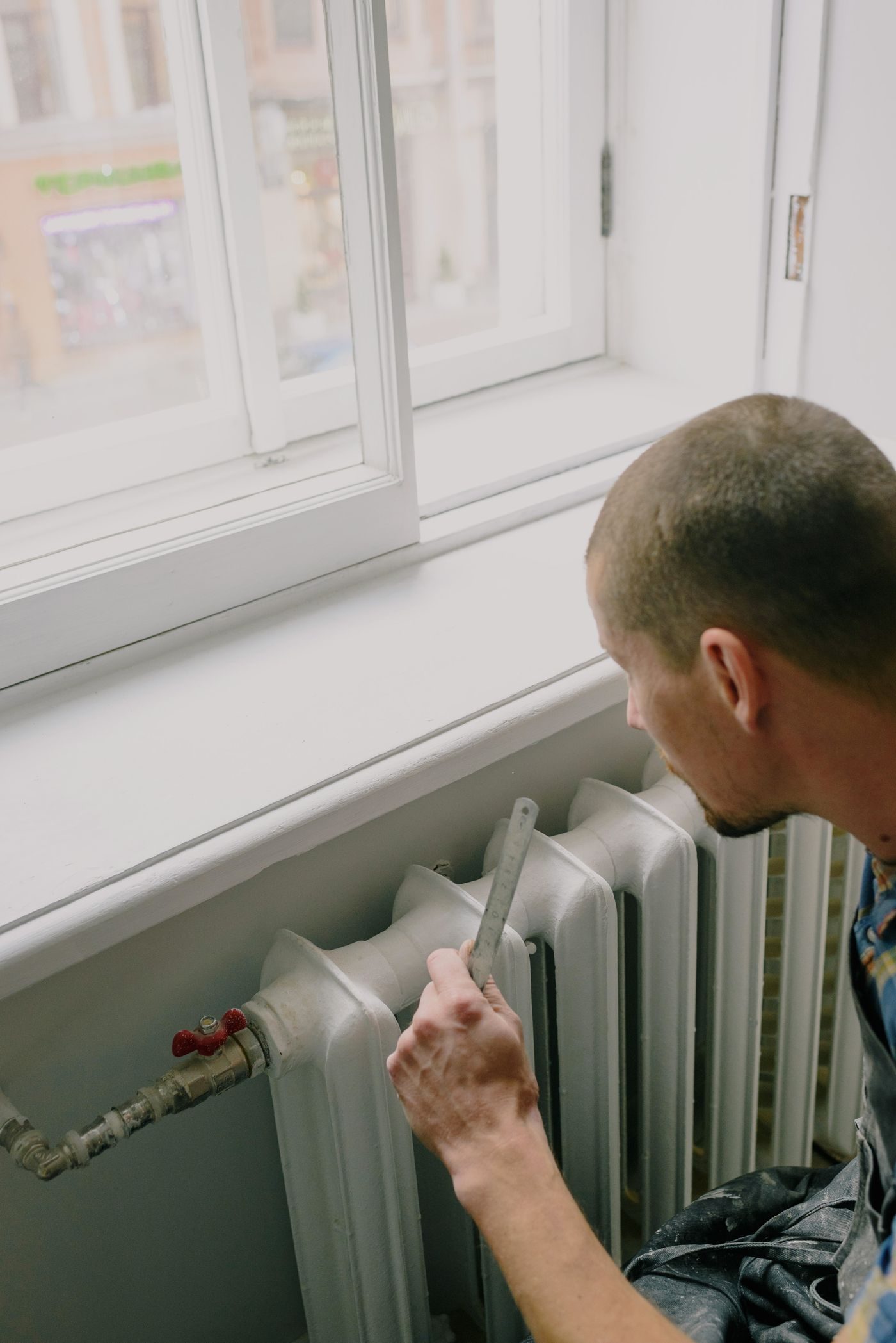 Engineer measuring beside a radiator under a bright window